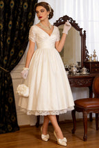 1950s vintage short A-line wedding dress with sleeves, V-neck back, back zipper, tea-length hem with lace trim.